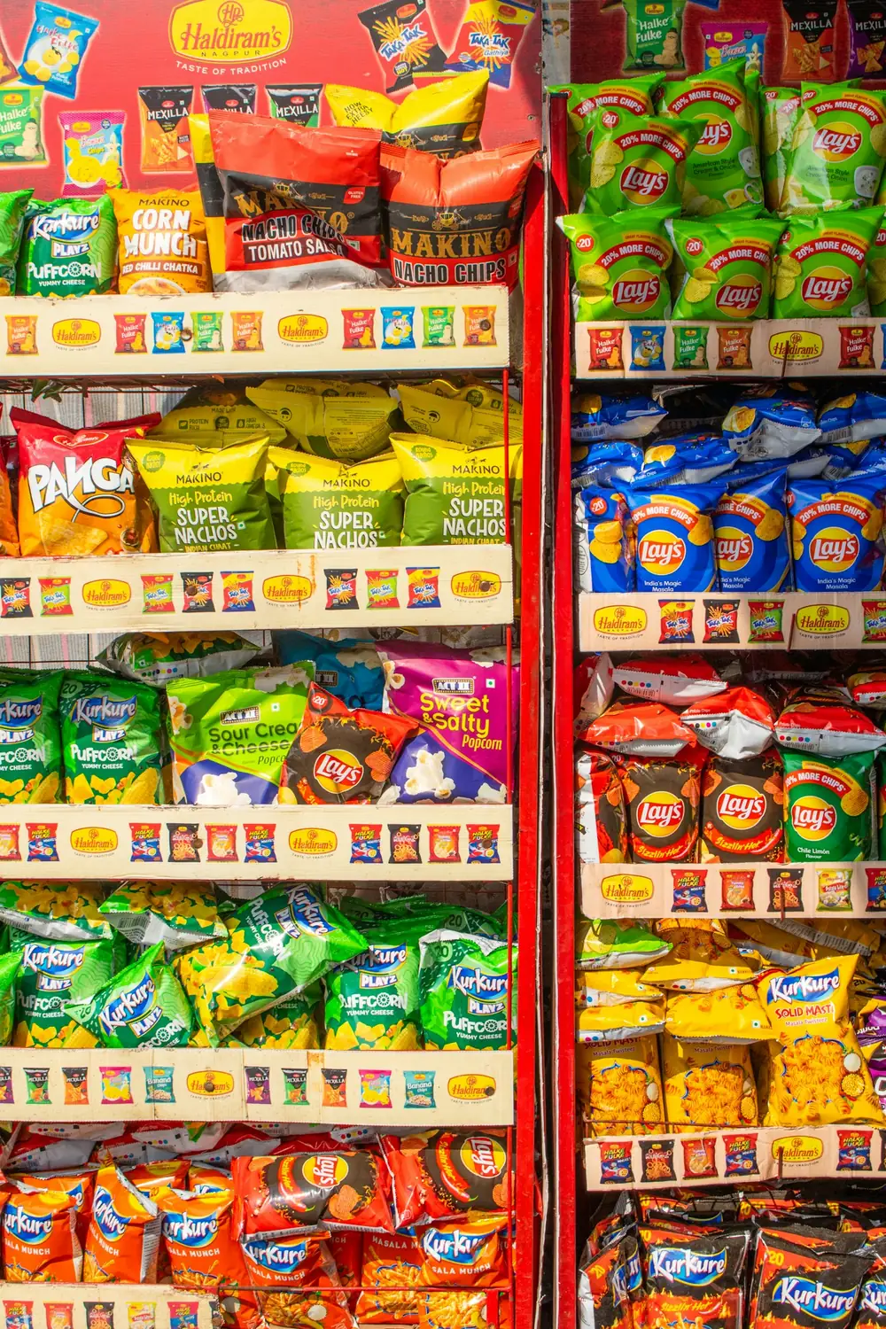 Branded snack displays with shelf-edge brand strips inside an Indian retail store — representative service image